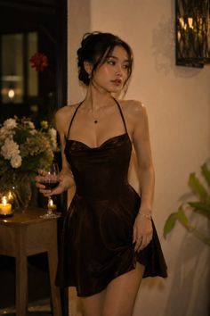 Woman in a dark halter dress holding a wine glass indoors