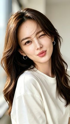Woman with long brown hair winking and pouting in a white t-shirt