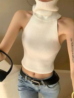 Person in a white turtleneck top and light wash jeans with an exposed midriff