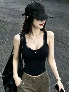 Woman in a black tank top and baseball cap outdoors