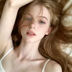 Woman with long red hair and blue eyes wearing a white top