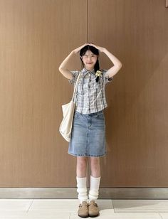 Young woman in a plaid shirt and denim skirt winking at the camera