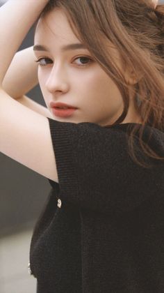 Woman with long brown hair in a black top, looking directly at the viewer