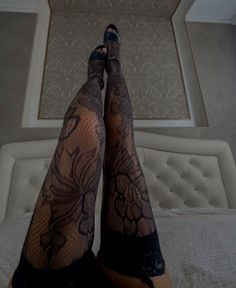 Legs in black lace stockings and heels resting on a bed