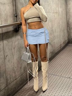 Woman in a one-shoulder crop top and mini skirt with high boots