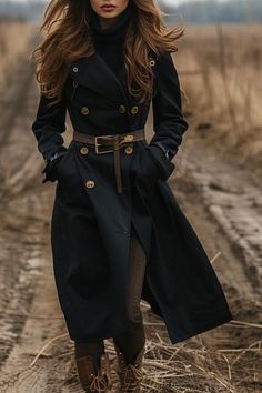 Woman in a black trench coat with a belt and boots walking outdoors