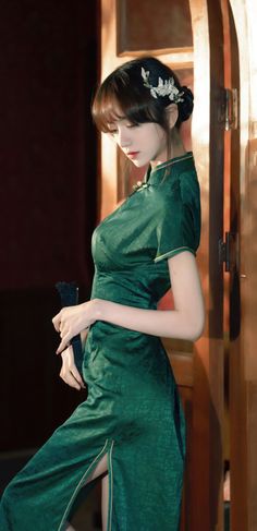 Woman in a green cheongsam with a traditional fan and hair ornament