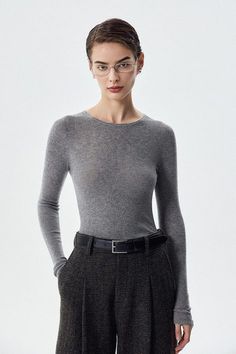 Woman with short hair and glasses wearing a gray top and plaid pants