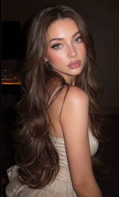 Woman with long brown hair wearing a white dress, looking over her shoulder