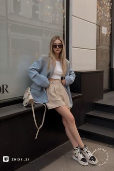 Woman with blonde hair and sunglasses wearing a crop top and blazer outdoors