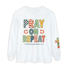 White long sleeve shirt with colorful 'PRAY ON REPEAT' text and a cross design