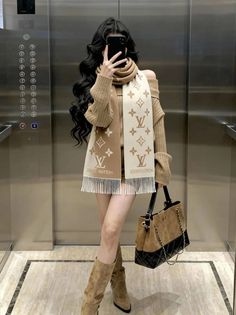 Woman in an off-shoulder sweater and scarf taking a mirror selfie in an elevator