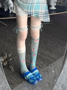 Person wearing fishnet stockings, floral socks, and a plaid skirt