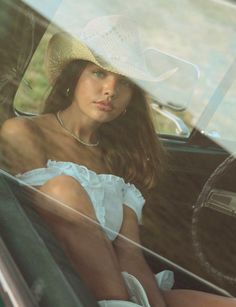 Woman in a cowboy hat and off-shoulder top sitting in a car
