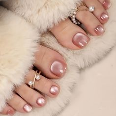 Feet with pink nail polish and pearl toe rings on a furry surface