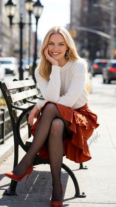Blonde woman in a white sweater and red skirt sitting on a park bench