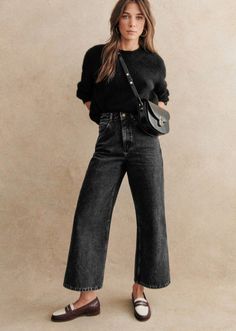 Woman in a black sweater and wide leg jeans with a crossbody bag