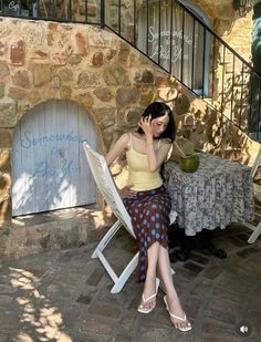 Woman with long hair sitting outdoors at a cafe with a polka dot skirt