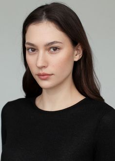 Woman with long dark hair wearing a black top, looking directly at the camera