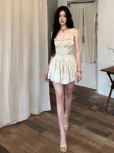 Woman in a white mini dress and high heels standing indoors