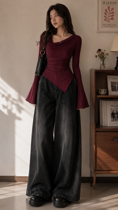 Woman with long hair wearing a burgundy top and wide leg jeans indoors