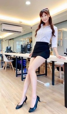 Woman in a white shirt and black mini skirt posing in an office