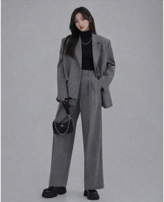Woman in a gray suit and black turtleneck with a shoulder bag