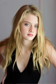 Young woman with blonde hair and blue eyes wearing a black top