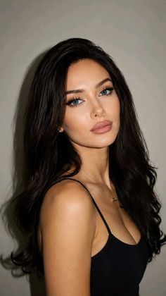 Woman with long dark hair and blue eyes wearing a black top and necklace