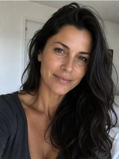 Woman with long dark hair in a deep v-neck top indoors