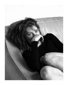 Woman with long hair lying on a couch, covering her mouth with her hand