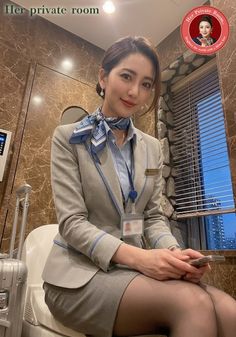 Woman in business attire with a scarf and earrings, holding a phone indoors