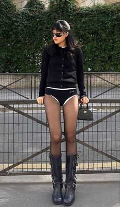 Woman in a black cardigan and underwear with tights and biker boots outdoors