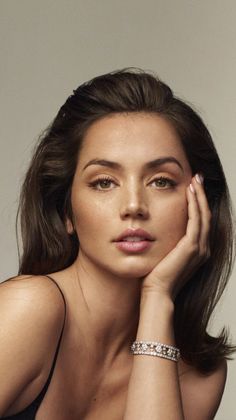 Woman with long brown hair wearing a black top and diamond bracelet