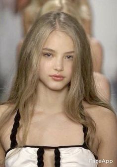 Young woman with long blonde hair wearing a white top with black straps
