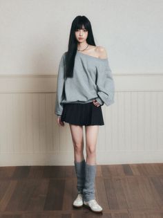 Woman with long black hair wearing an off-shoulder top and pleated skirt indoors