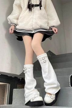 Person in a white fuzzy jacket and black skirt with white leg warmers and platform shoes