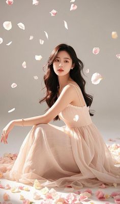 Woman in a light pink dress sitting on the floor with flower petals around her