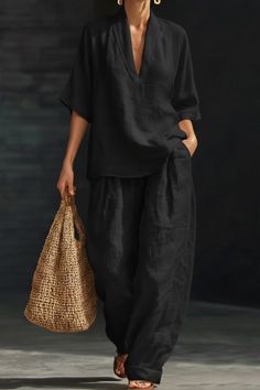 Person in a black linen outfit holding a straw bag