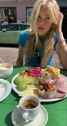 Blonde woman with long hair sitting at an outdoor cafe with a brunch plate