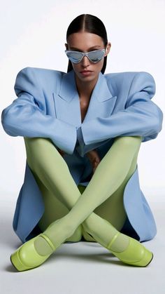 Woman in a blue blazer and lime green tights with sunglasses in a studio shot