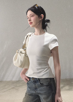 Woman with black hair wearing a white t-shirt and blue jeans, holding a shoulder bag