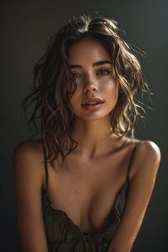 Woman with wavy dark hair and exposed skin against a dark background