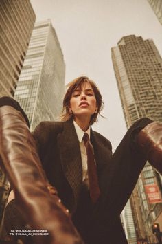 Woman in a suit and tie with brown boots in a city, viewed from a low angle