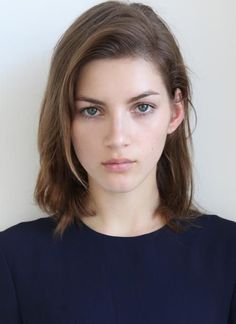 Woman with medium brown hair and blue eyes wearing a navy top