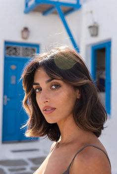 Woman with short brown hair in front of a white building with blue doors