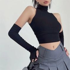 Woman in a black crop top and arm warmers with a gray pleated skirt