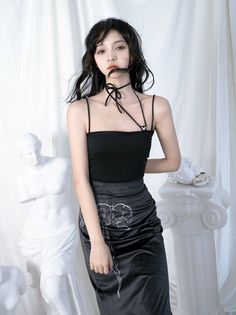 Woman in a black top and skirt with a choker standing indoors