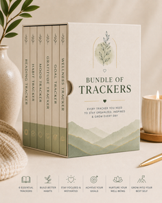 Bundle of tracker journals with a minimalist design, a candle, and a plant