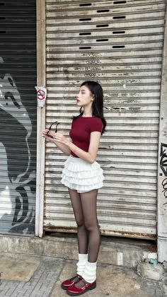 Woman in a red top and white ruffled skirt standing on a street